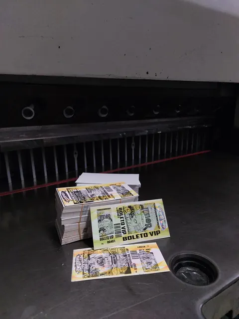 Boletos VIP numerados apilados sobre la guillotina del taller.