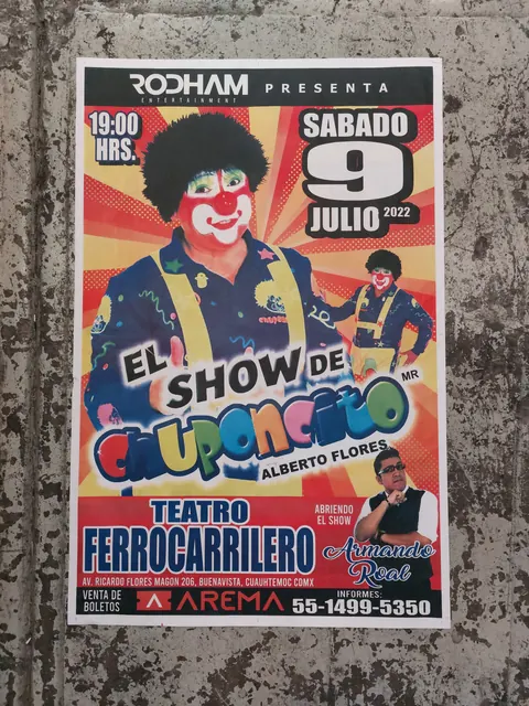 Póster a color impreso para un espectáculo en teatro, pegado en una pared.